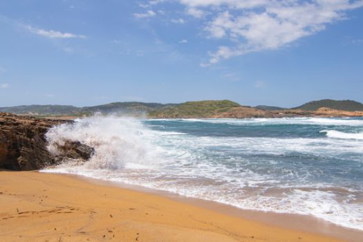 Olas rompiendo en las rocas que rodean una cala