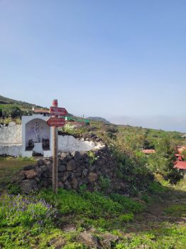Señalización por el barrio de La Sabina al lado de una de la cruces tradicionales palmeras junto al Camino Viejo.