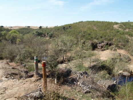 El Camino mino se dirige a un puente de piedra para superar un reguero