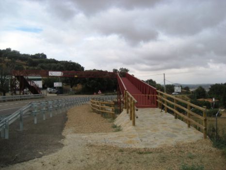El camino cruza sobre la carretera por una pasarela metálica